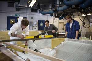 Apprentices Adam West (left), aged 28, and Dan Funnell (right), 19, ensuring frames are fitted level before gluing. Lecturer Darren Patten cleaning up in the back