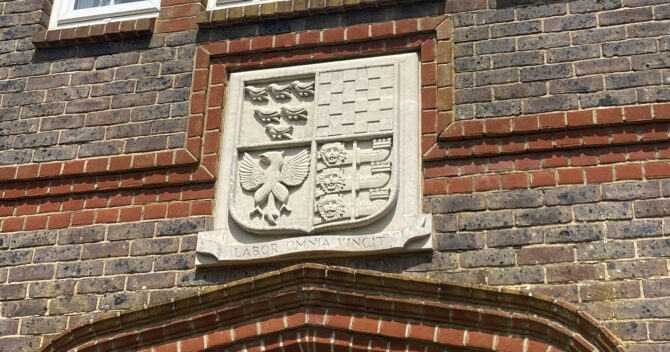 Latin motto and coats of arms highlighted in piece above doorway feat | FE Week